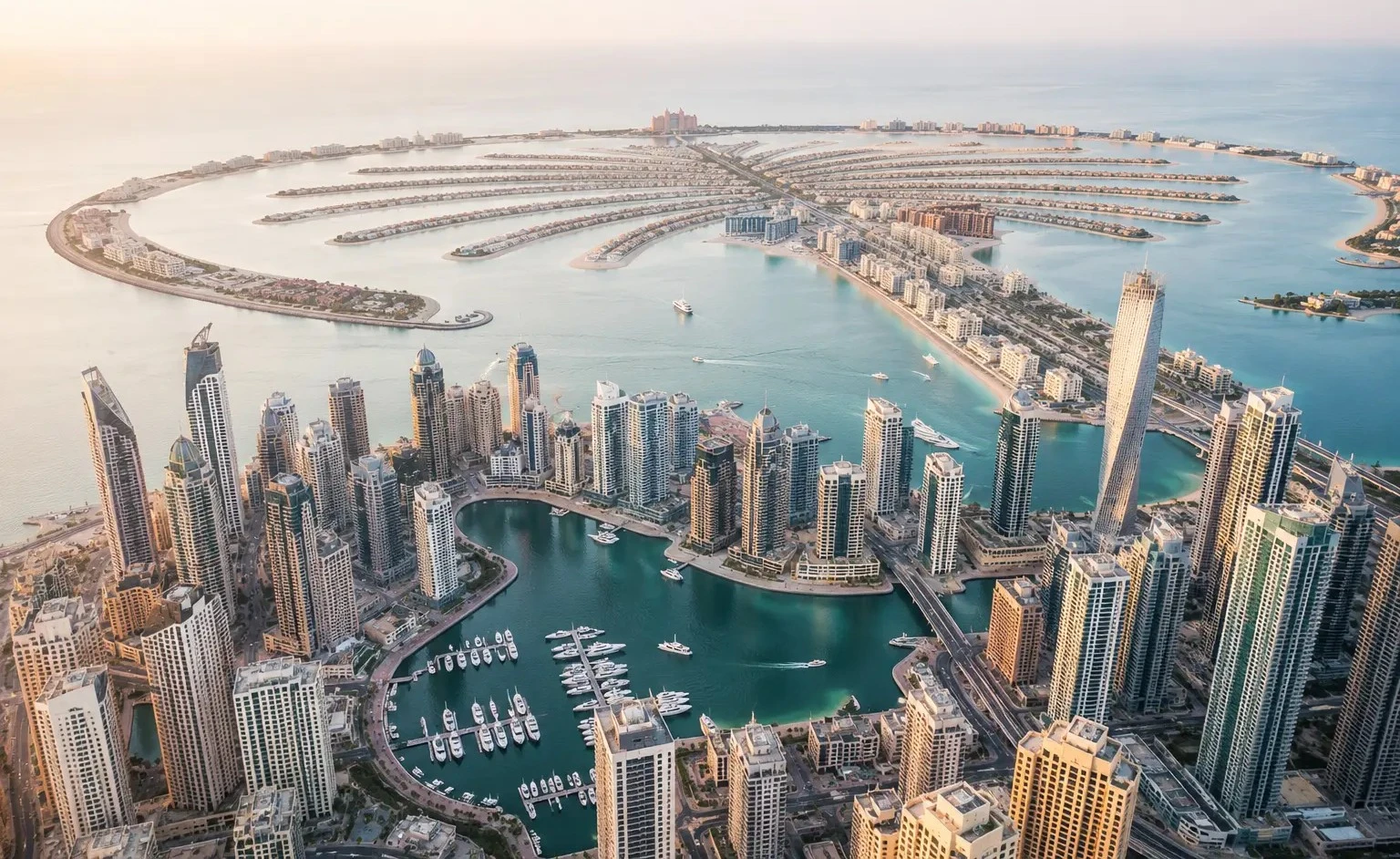 Palm Jumeirah and Emaar Beachfront viewed from above at dusk, showing freehold villa and apartment communities that qualify for UAE Golden Visa property investment.